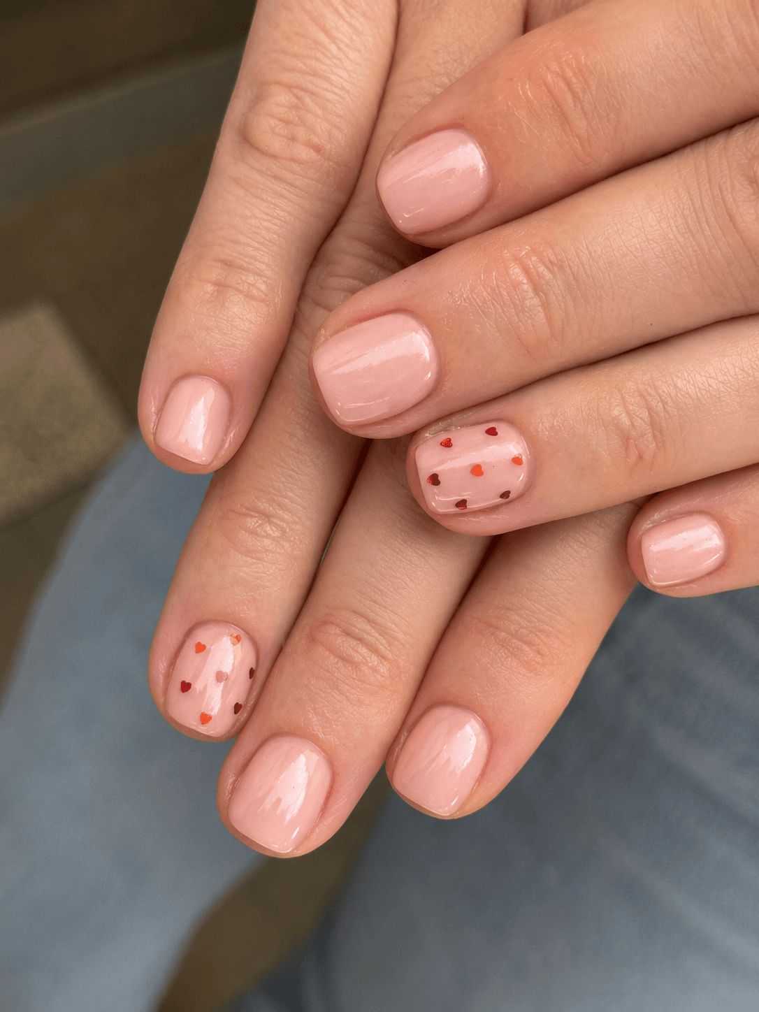 Soft pink nails with tiny red and coral heart accents