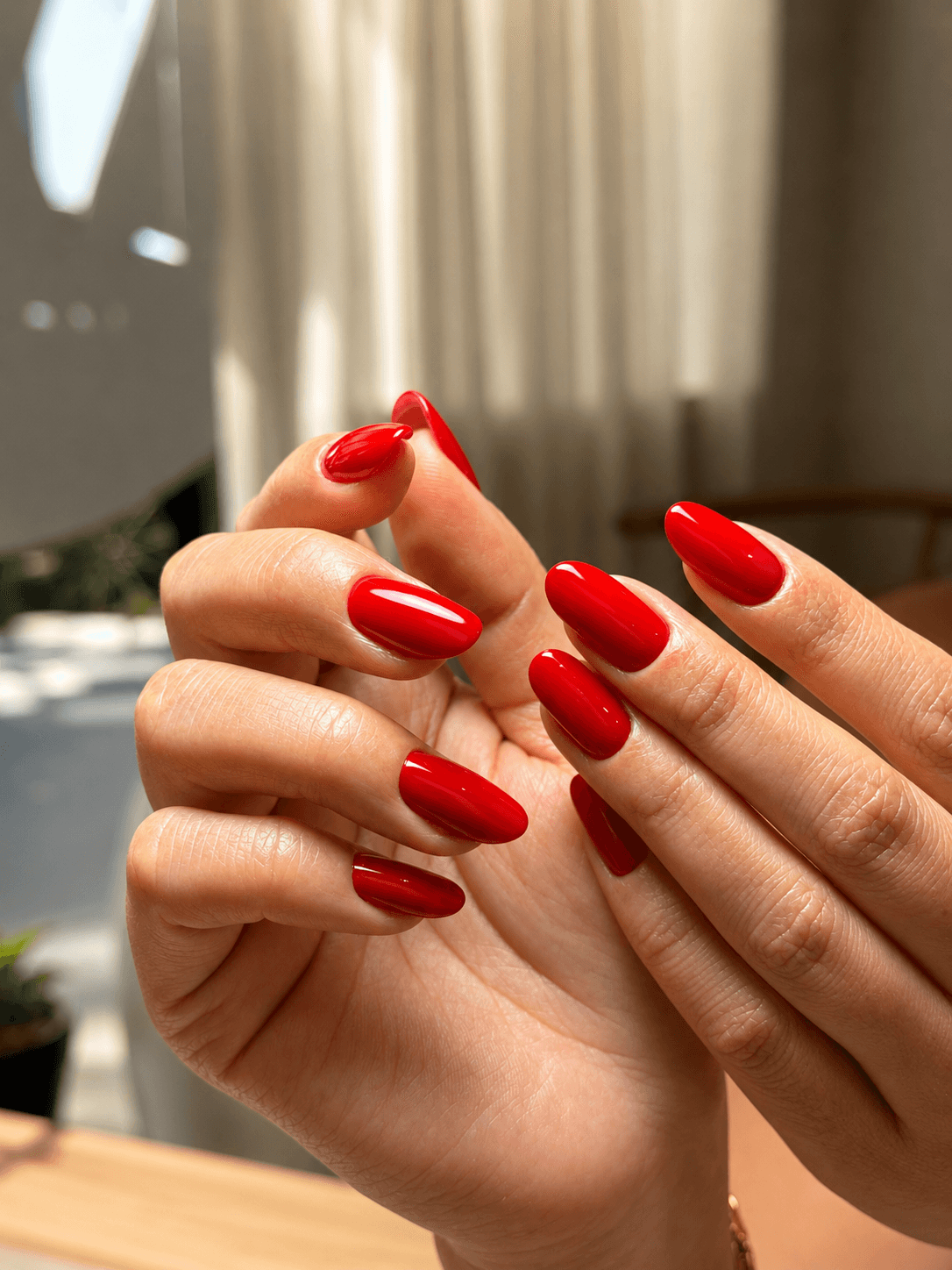 Bold glossy red almond nails in natural light